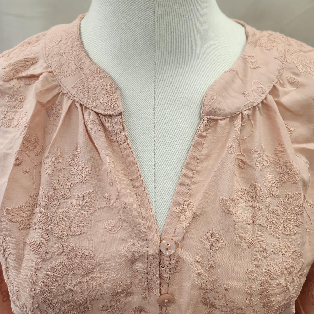 Detailed view of neckline of peach buttoned top
