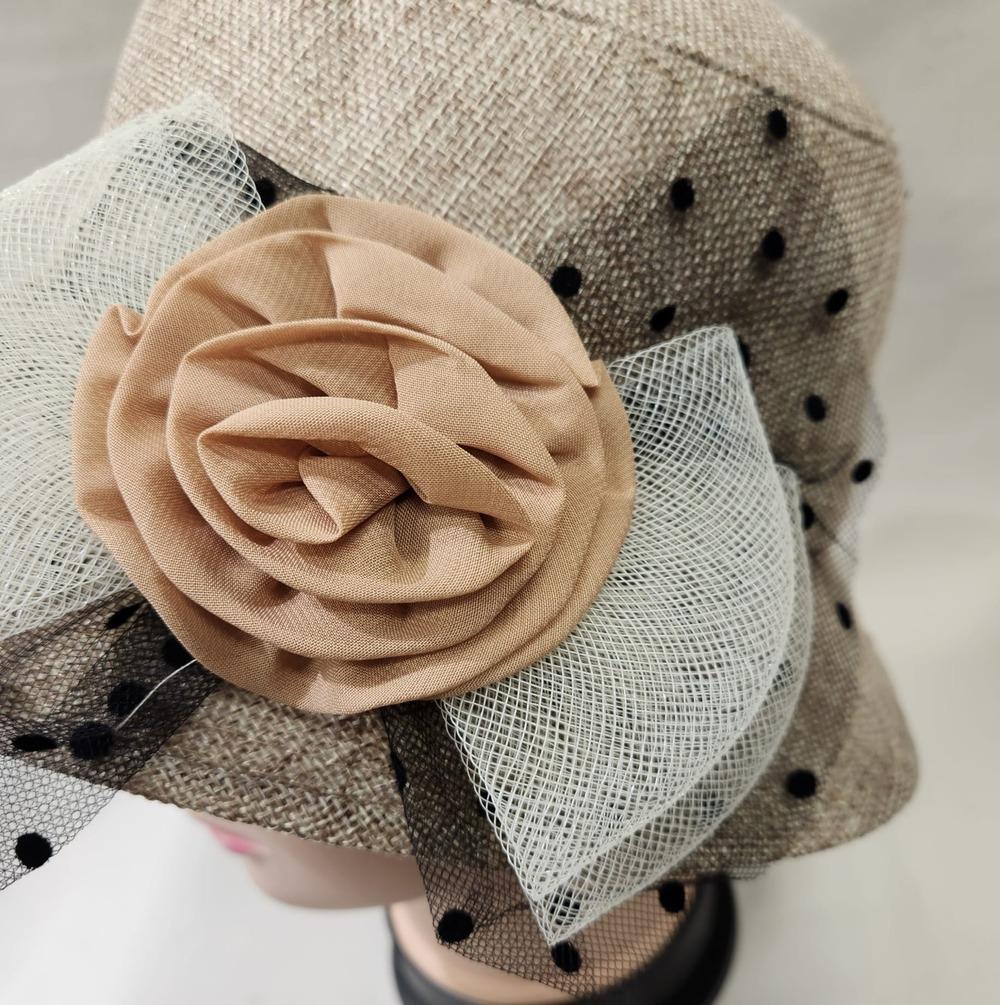Detailed view of embellishments on beige cloche hat