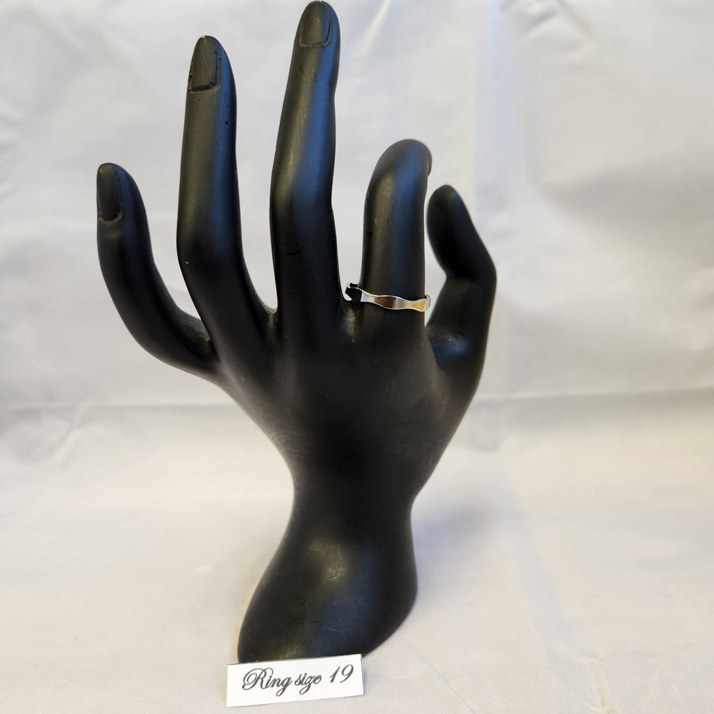 Silver colored wave band ring on a mannequin stand