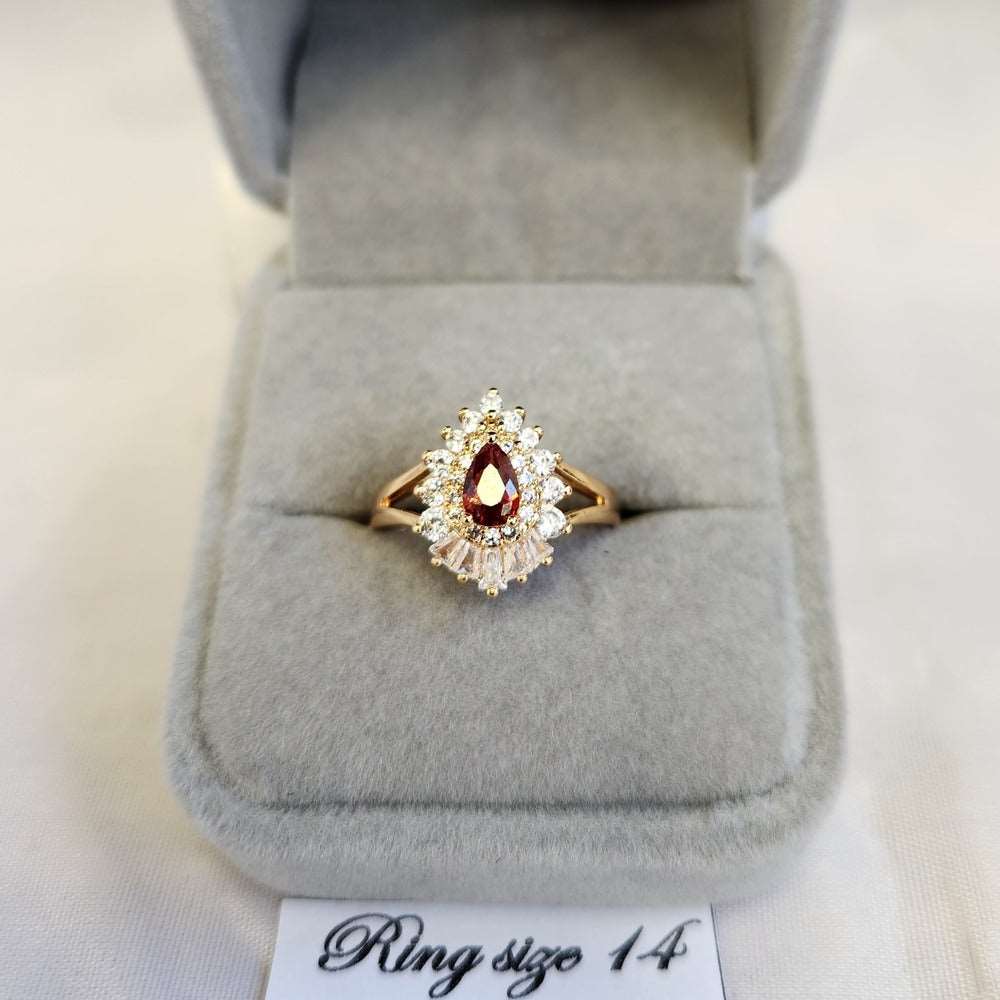 Delicate gold color ring with orange pear shaped center stone