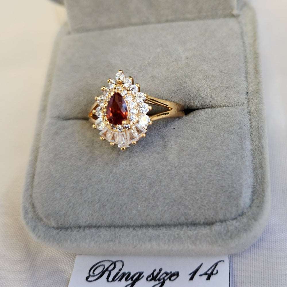 Detailed view of gold color ring with orange pear shaped center stone