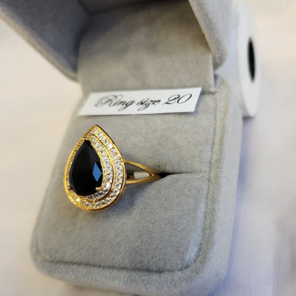 Detailed view of Gold color ring with black pear shaped center stone