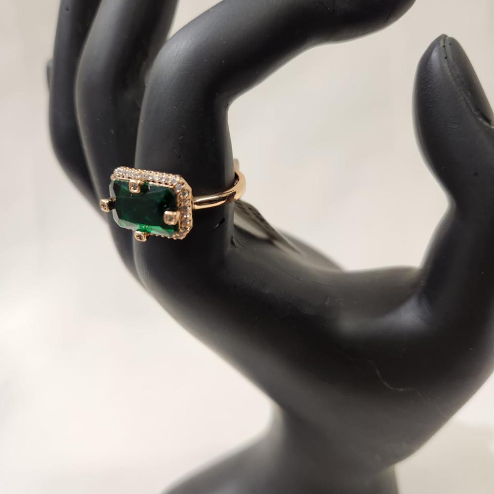 Detailed view of Gold ring with green baguette shaped center stone