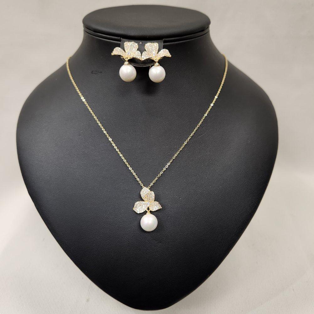 Front view of gold hued jewelry set with stones and pearls