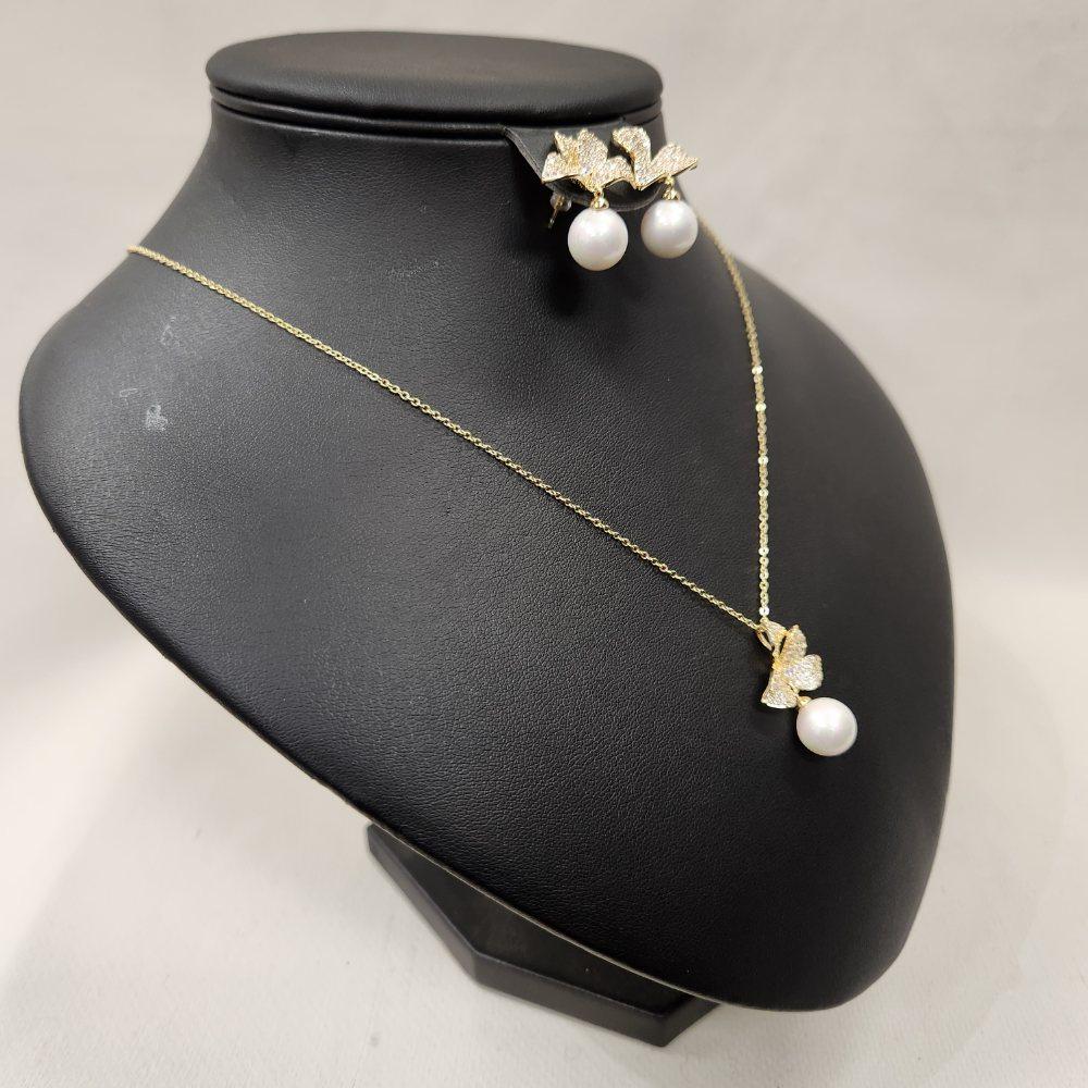 Side view of gold hued jewelry set with stones and pearls