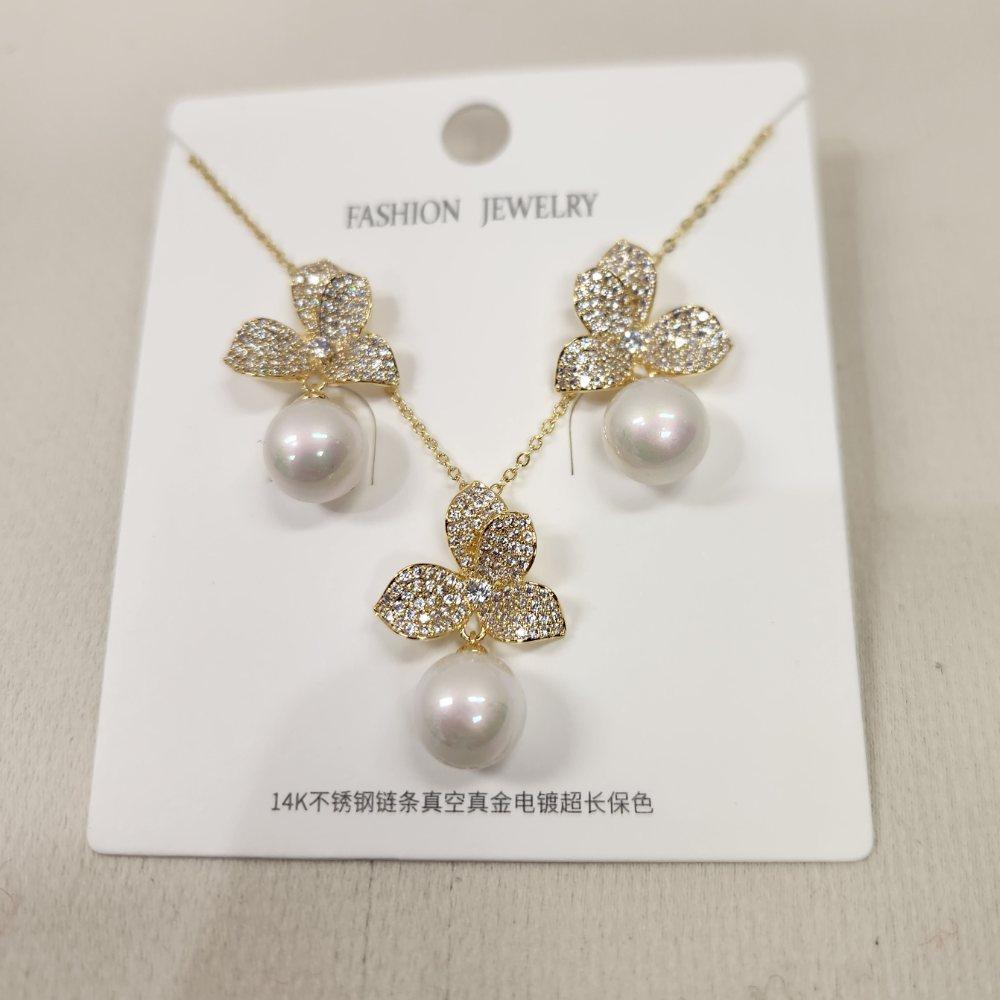 Detailed view of gold hued jewelry set with stones and pearls