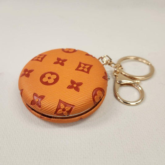 Orange Pocket mirror with engraved floral pattern and a keyring when closed