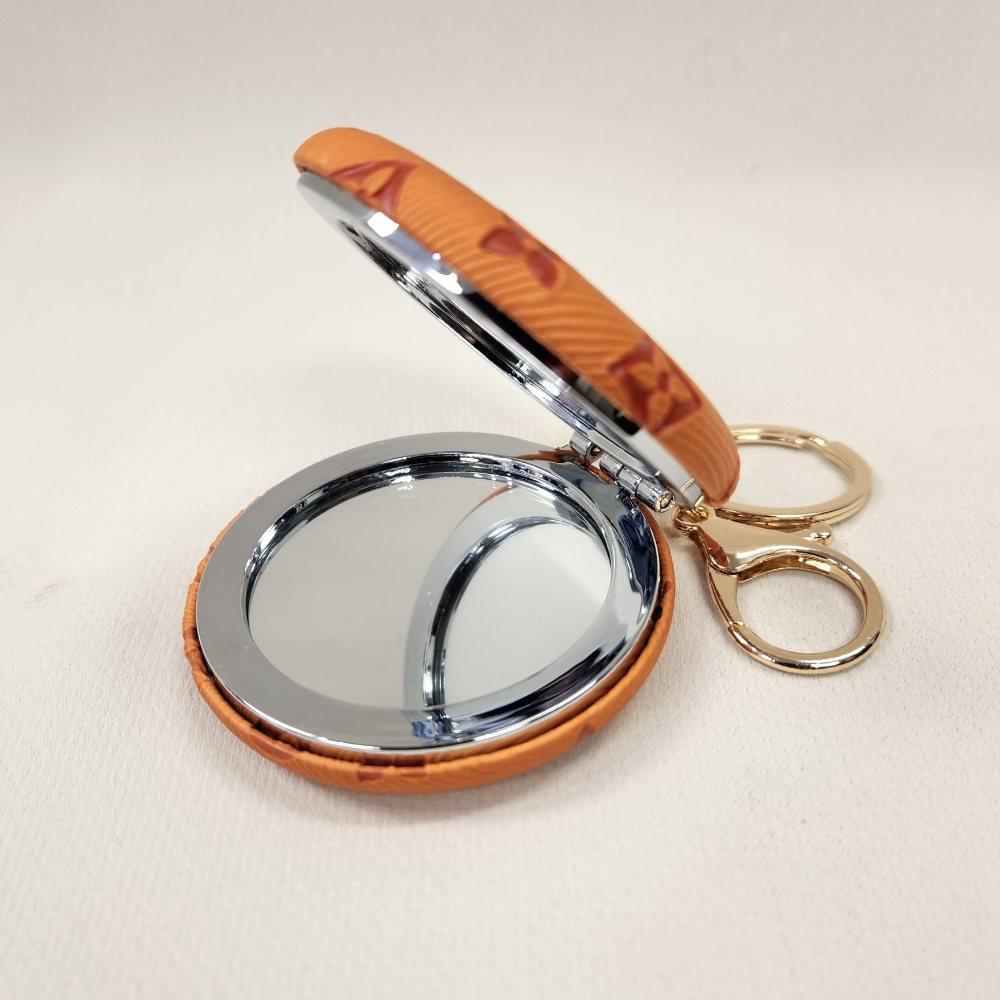 Orange Pocket mirror with engraved floral pattern and a keyring when opened