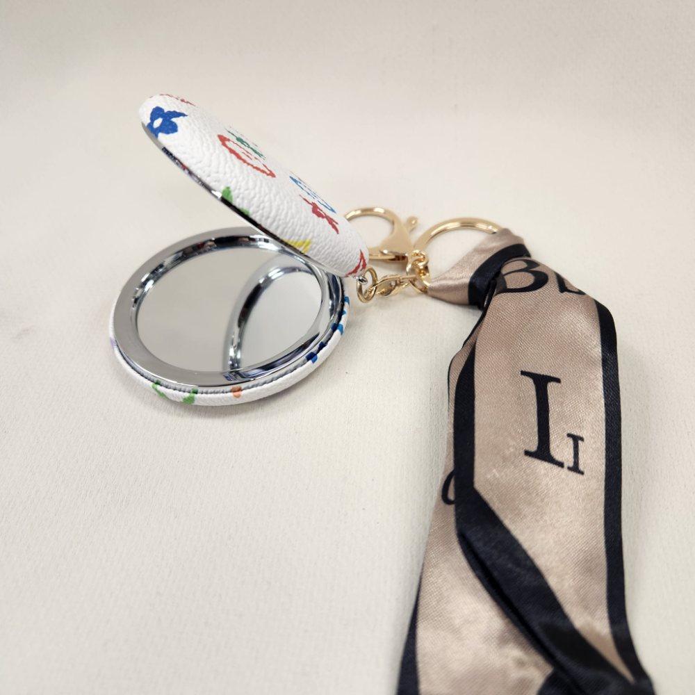 White Pocket mirror with colorful floral pattern and a keyring when opened