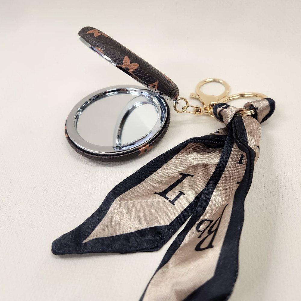 Brown Pocket mirror with tan floral pattern and a keyring when opened