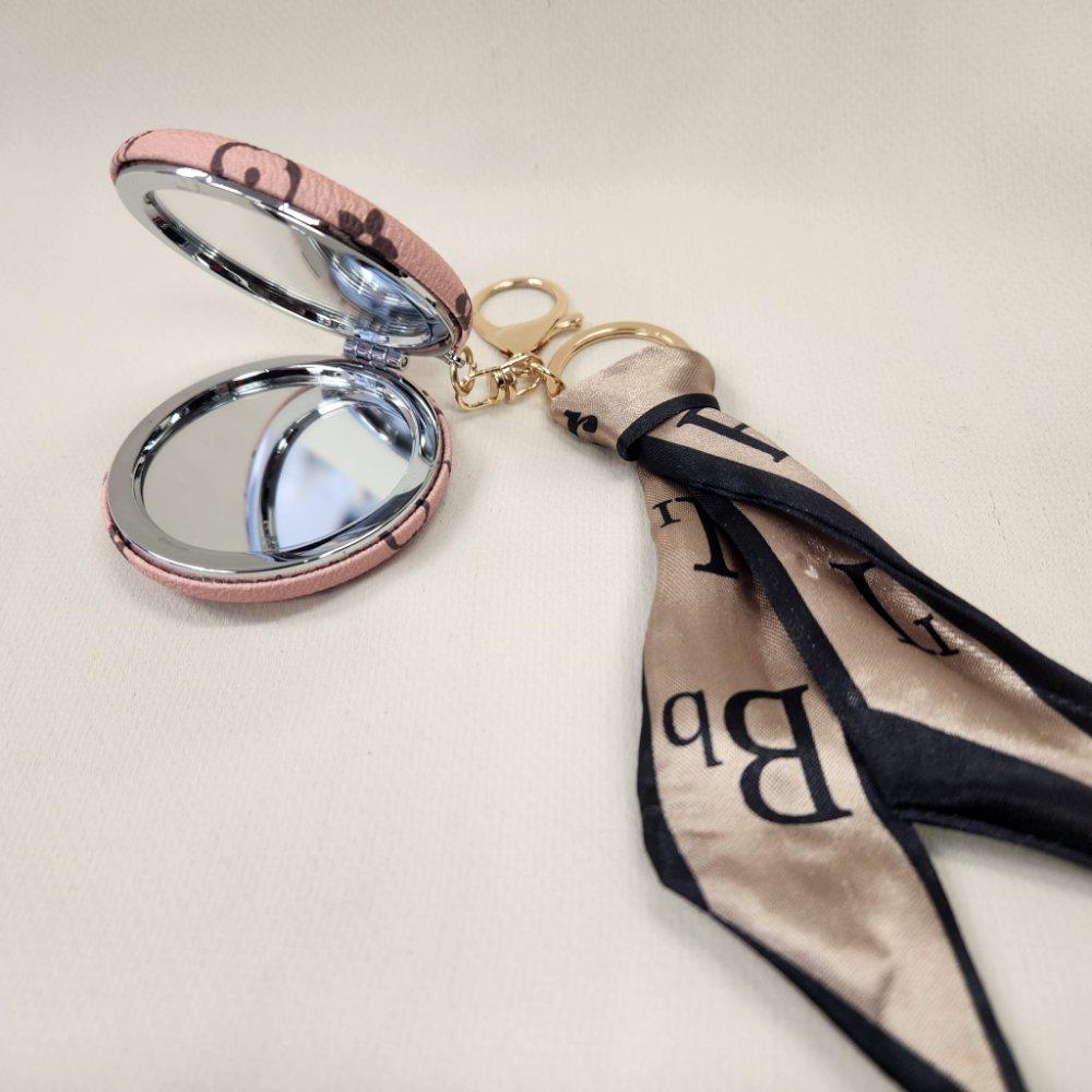 Pink Pocket mirror with brown floral pattern and a keyring when opened