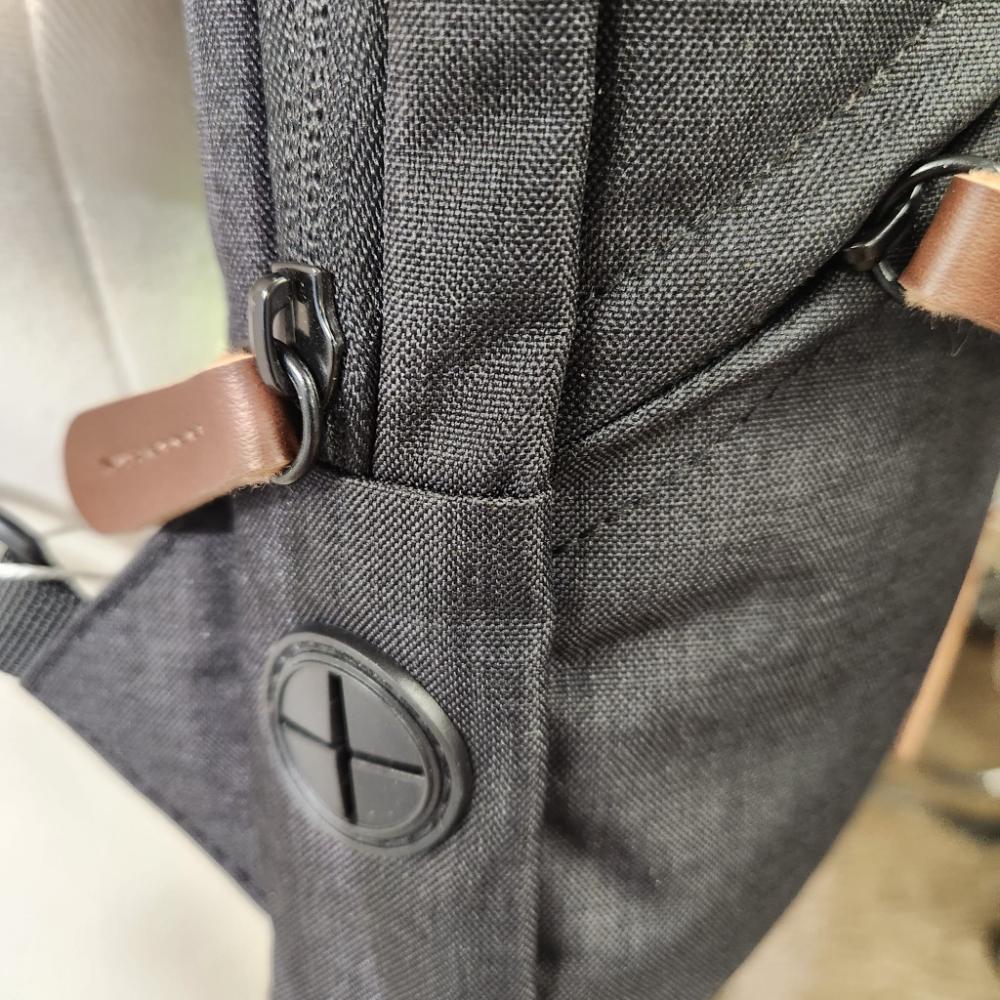 Detailed side view of Multi pocket black side bag with tan details