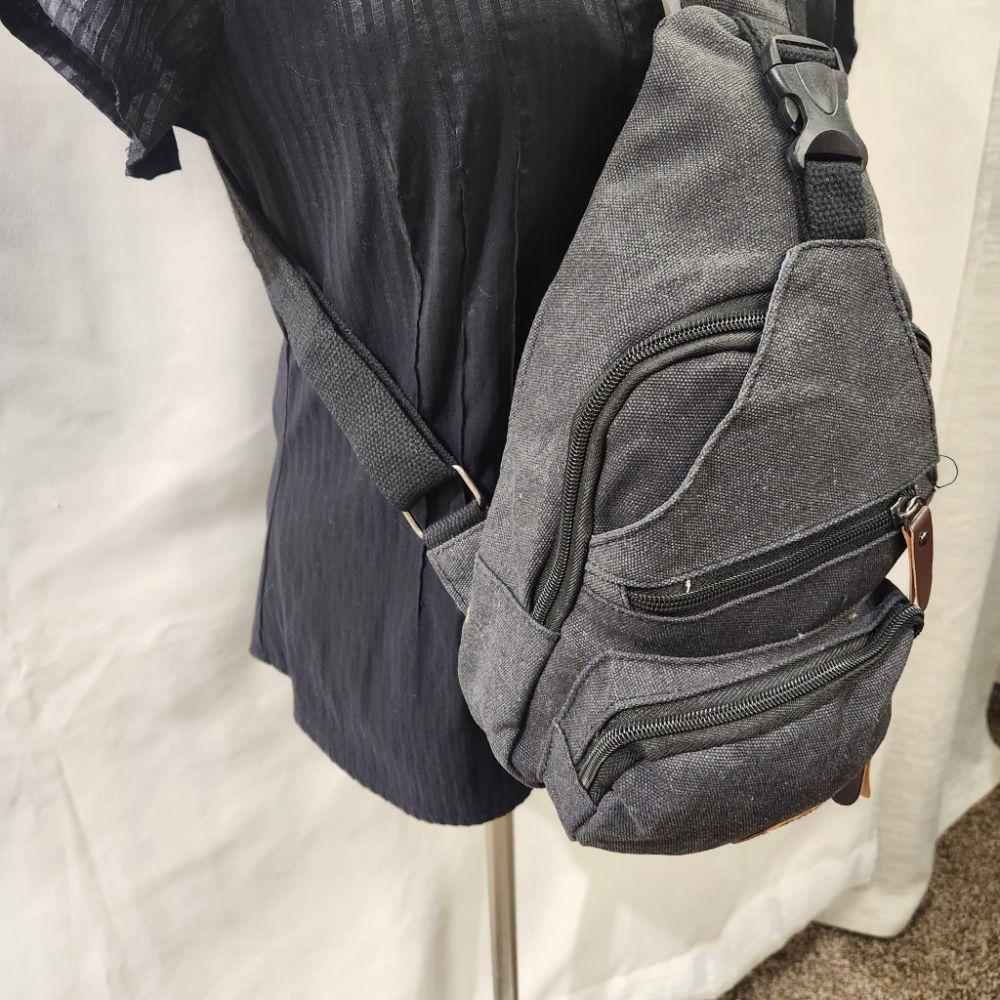 Side view of Greyish black side bag with multiple pockets