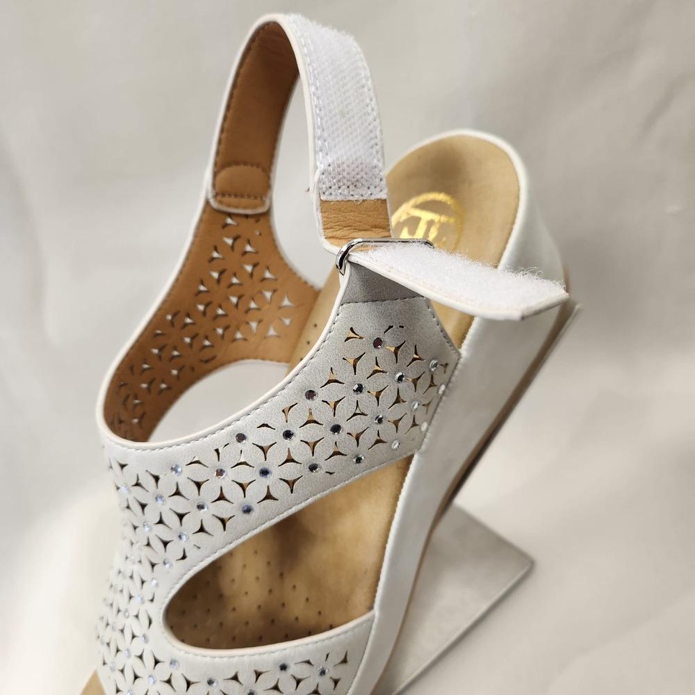 View of velcro closure of white summer sandals with flowery cutwork