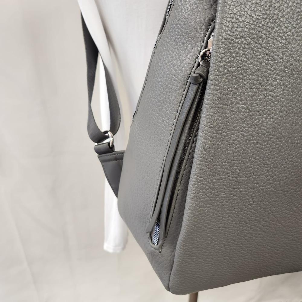 View of vertical side pocket on the side of grey backpack