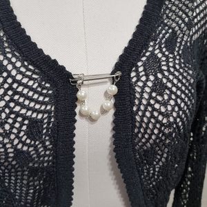 Detailed view of pearl lapel on black crochet shrug