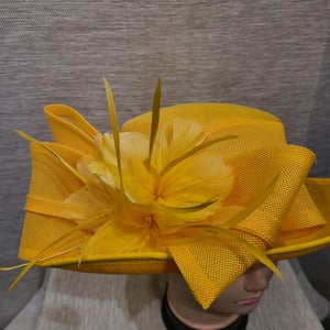 Detailed view of bow and feathers on yellow formal dress hat