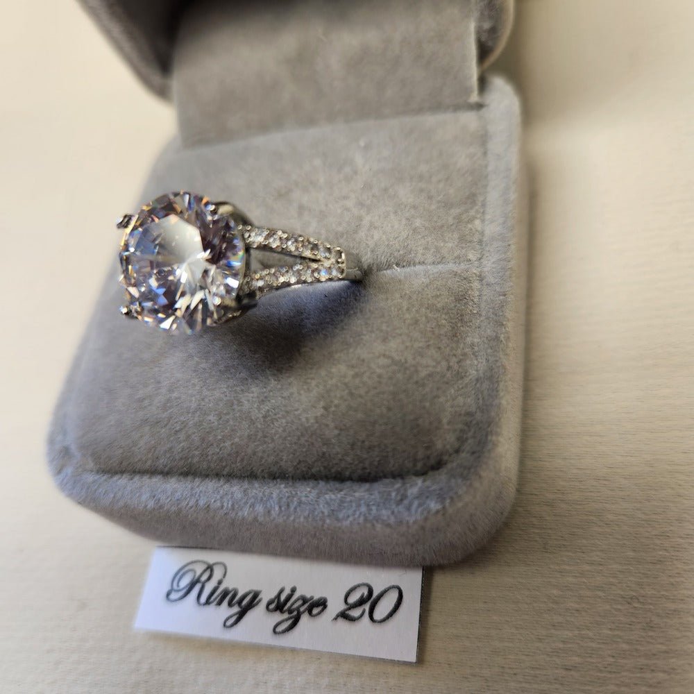 Detailed view of prong-set silver colored ring with clear stones