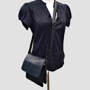 Leather side bag for women in black with front flap and an adjustable shoulder strap