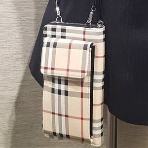 Closer view of small black strap plaid pattern side bag with cell phone compartment