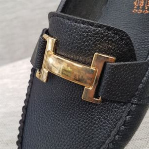 Detailed view of black loafer's top buckle
