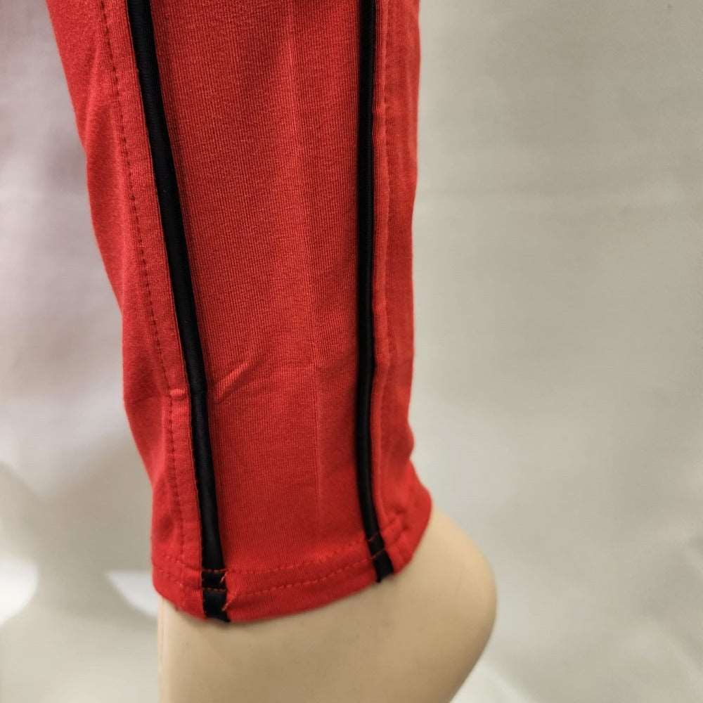 Detailed view of red leggings with black piping