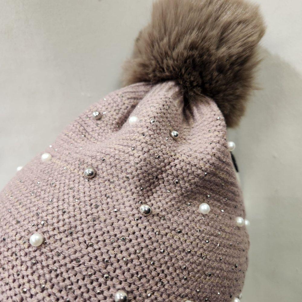 Detailed view of pom Pom of taupe colored beanie