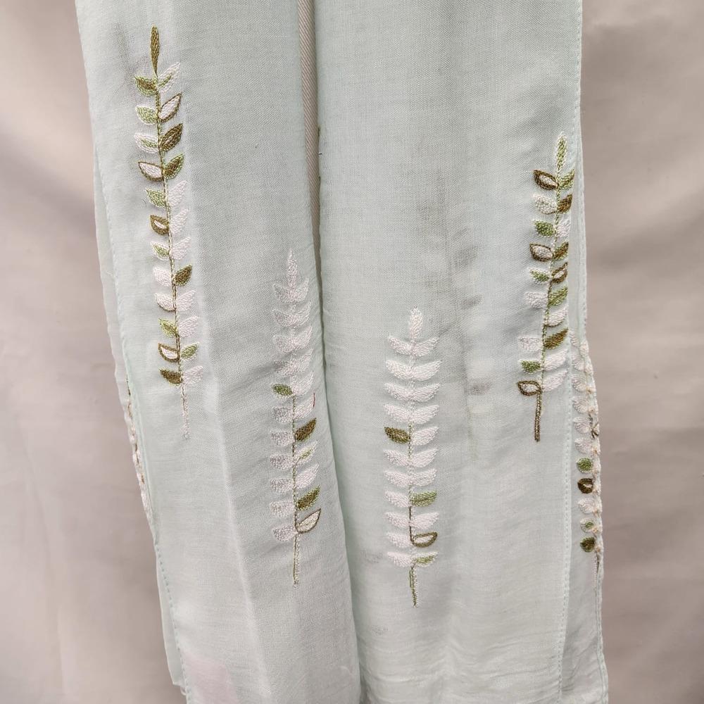 Detailed view of tasseled and embroidered border of pastel green scarf