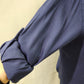 Detailed view of roll up sleeves of navy blue dress shirt