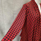 View of sleeves of Light open front top in red with black houndstooth pattern