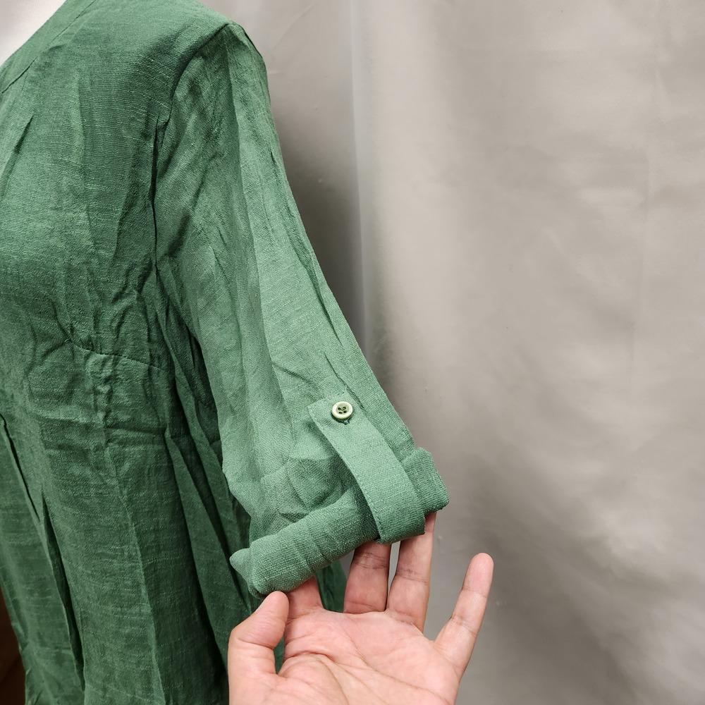 Detailed view of rolled up sleeves of green summer top