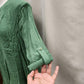 Detailed view of rolled up sleeves of green summer top