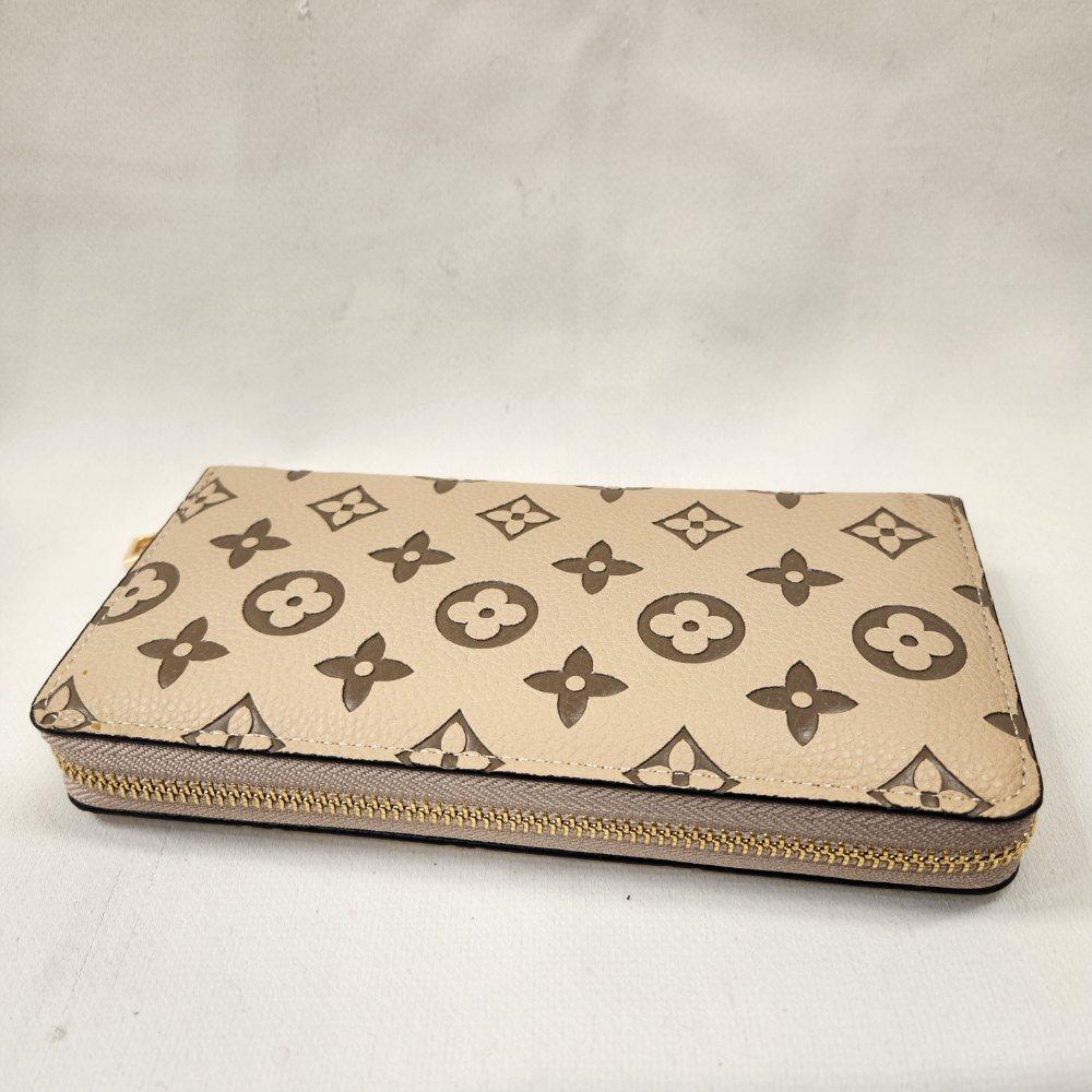 Gold hardware of beige wallet with brown floral pattern