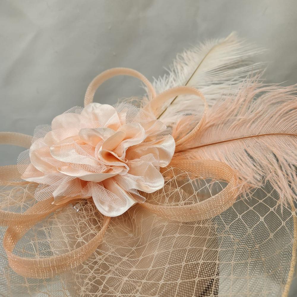 Detailed view of Elegant peach colored fascinator with veil