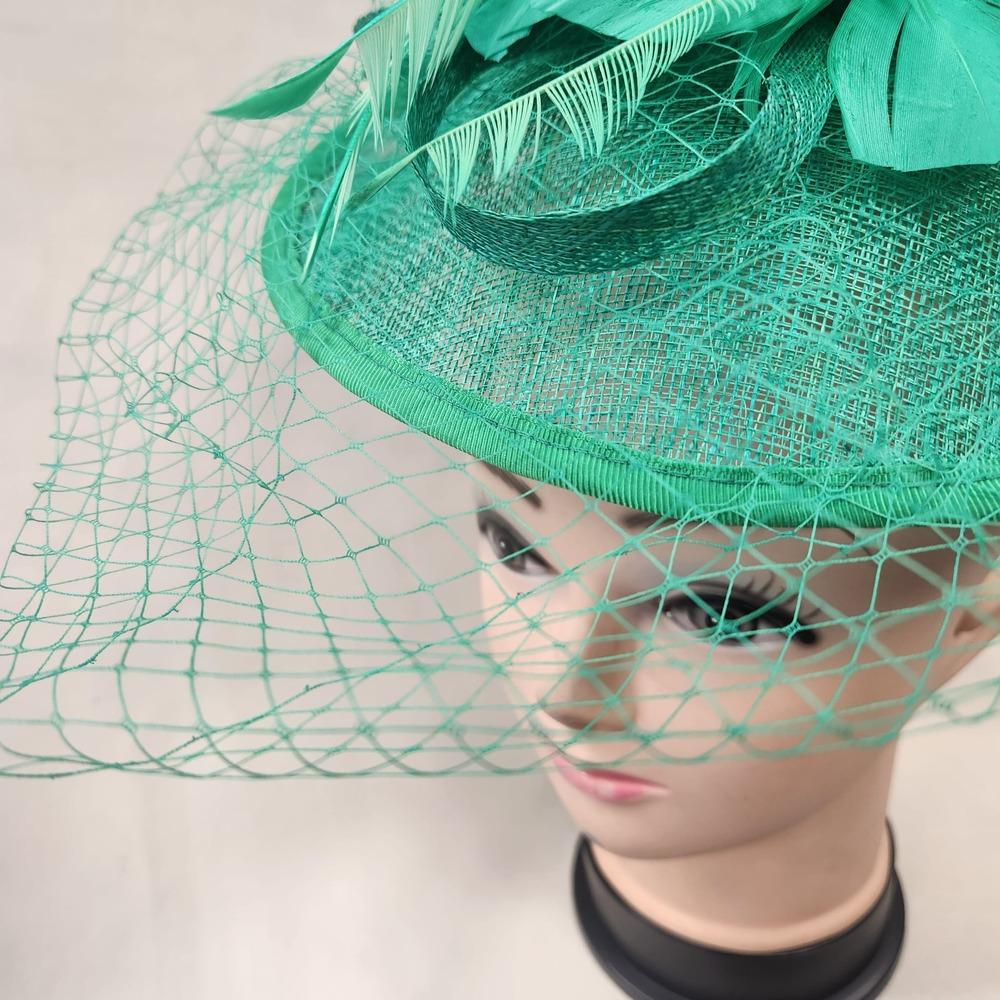 Front detailed view of green fascinator with veil