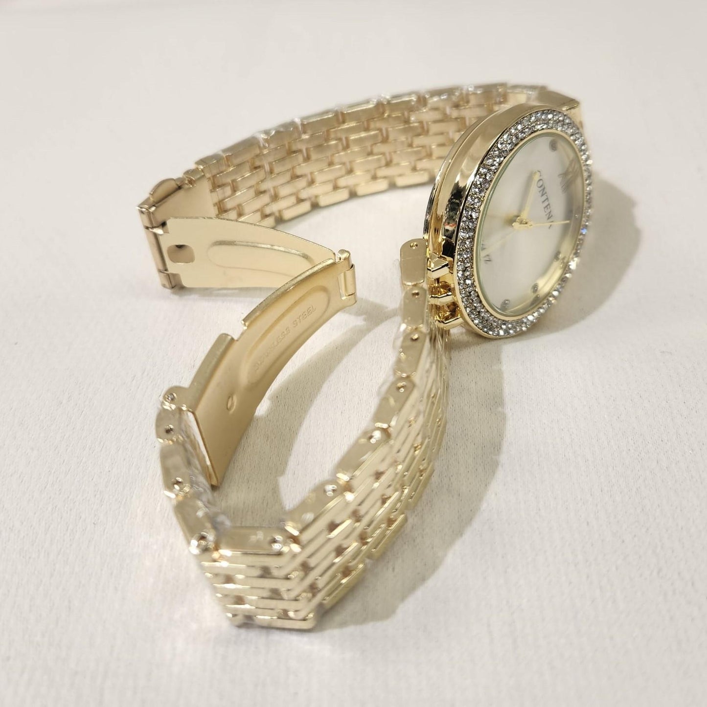 Folding clasp of gold watch with stone studded face