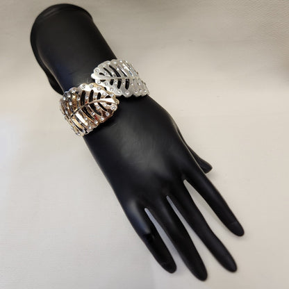Leaf shaped dual tone hinged bracelet on a mannequin stand