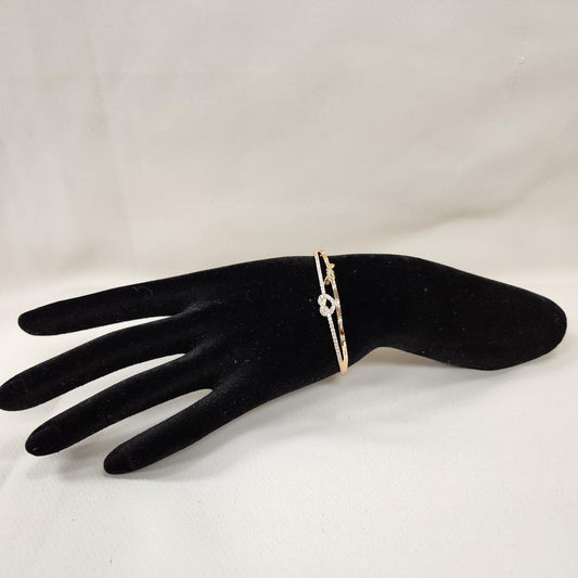 Dainty heart & bow gold bracelet displayed on a stand