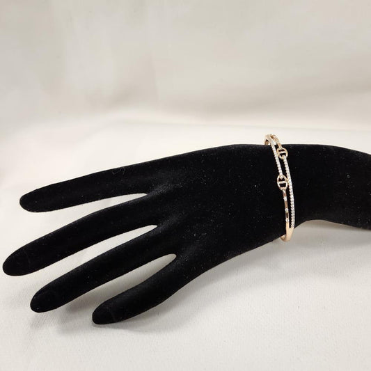 Dainty gold bracelet with clear stones displayed on a stand