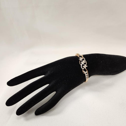 Dainty gold bracelet with floral design displayed on a stand