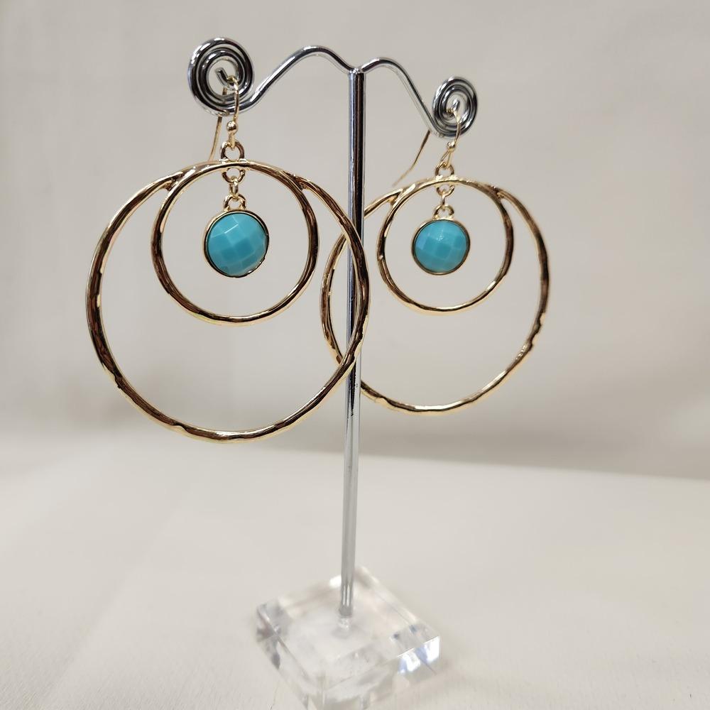 Dangle earrings with concentric loops displayed on a stand