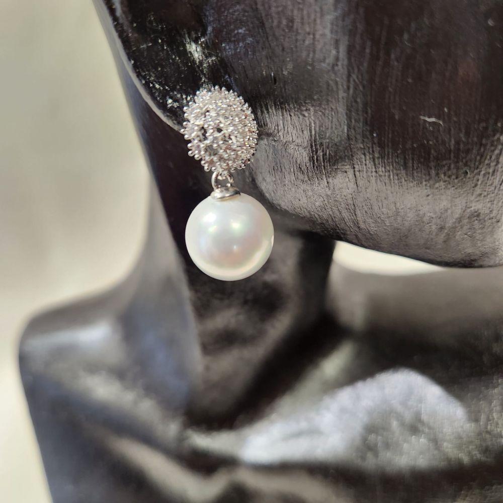 Detailed view of delicate earrings with stones and dangling pearl