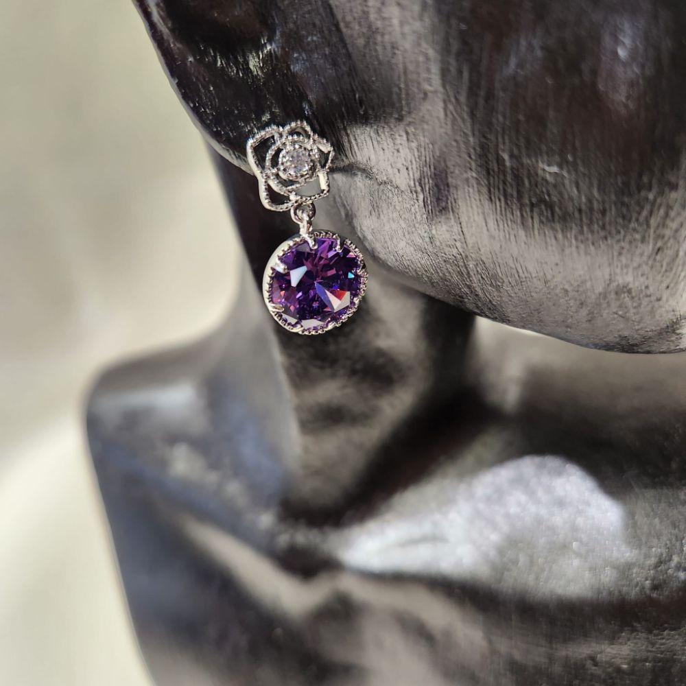 Detailed view of dangle earrings with clear and purple stone 