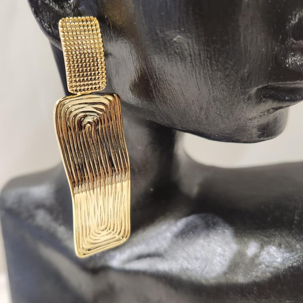 Detailed view of varying textured surfaces of modern gold earrings