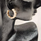 Side view of Gold ribbed huggie hoop earrings with stones