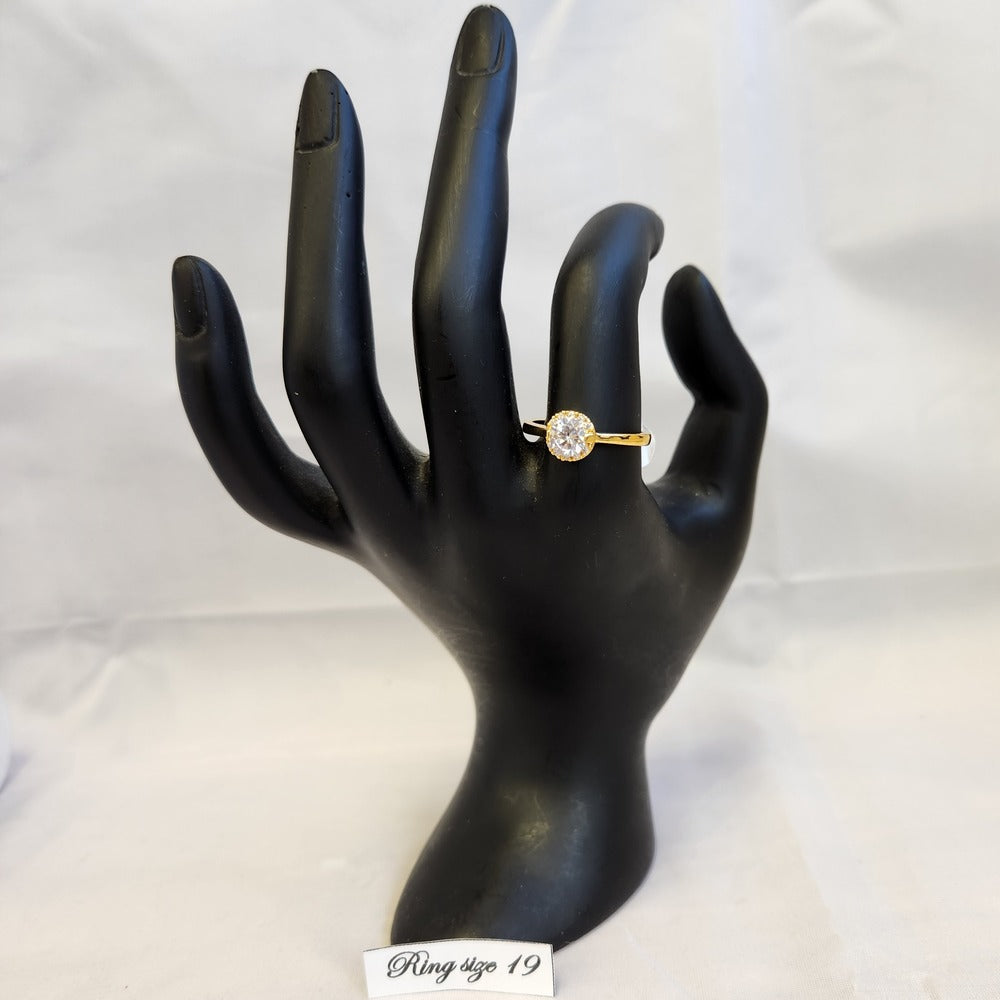 Simple halo style gold frame ring displayed on a mannequin stand