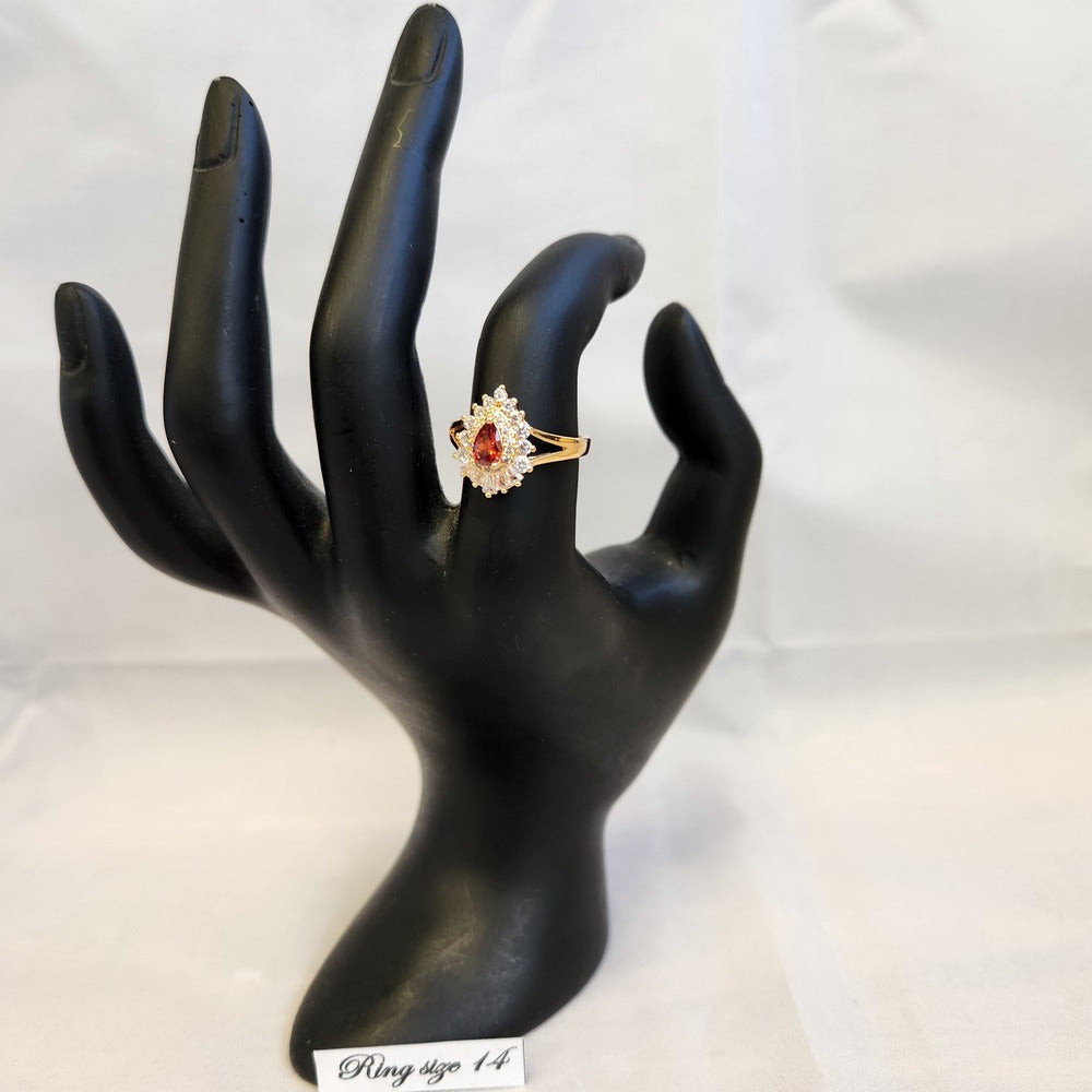 Ring with orange pear shaped center stone displayed on a mannequin stand