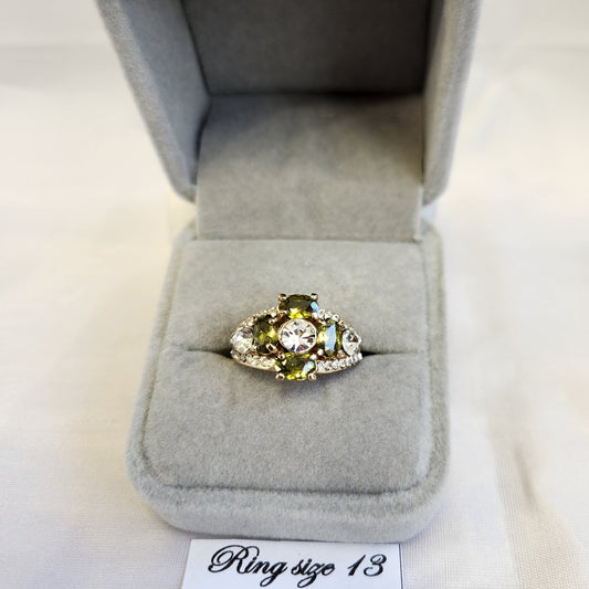 Gold frame ring with clear and green colored stone setting