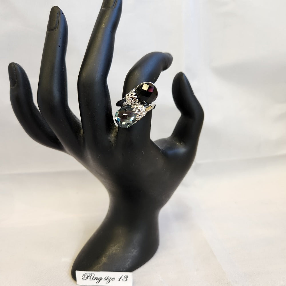 Bold silver color ring with black and grey stones displayed on a stand