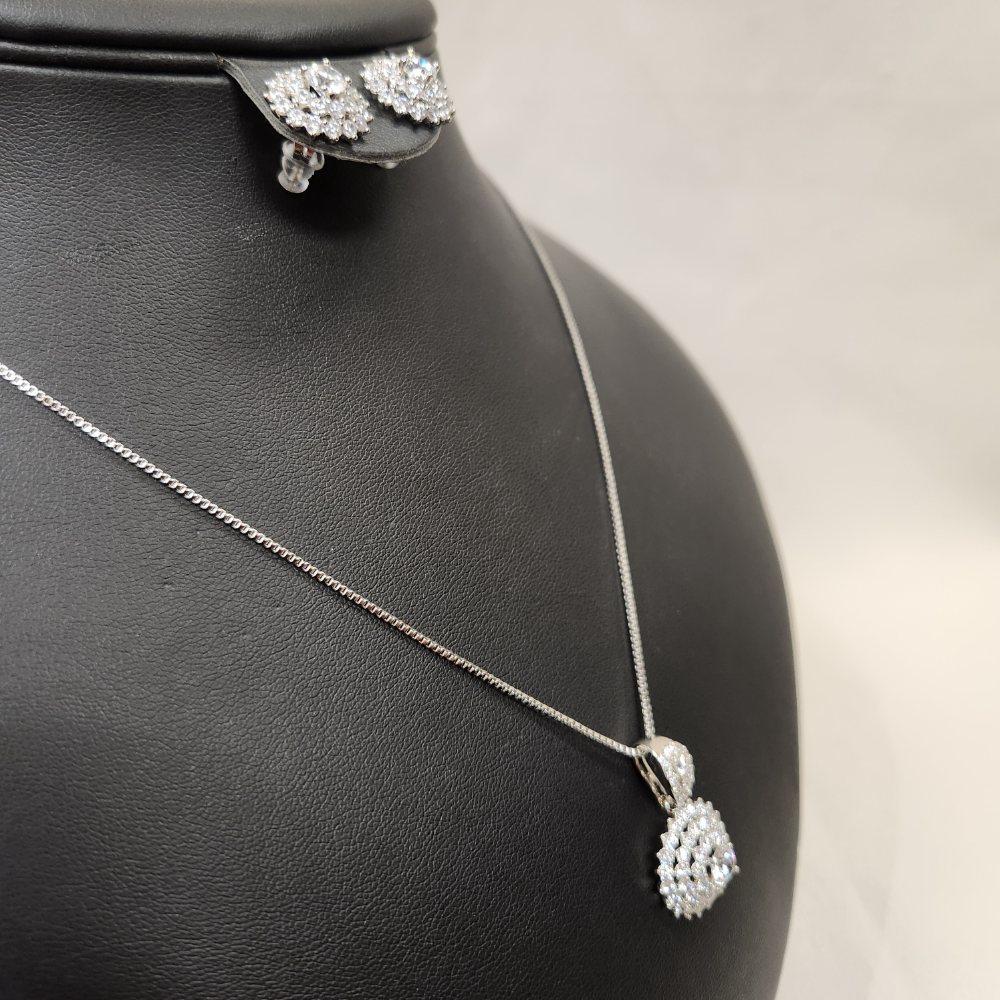 Side view of Three piece silver tone jewelry set with clear stones